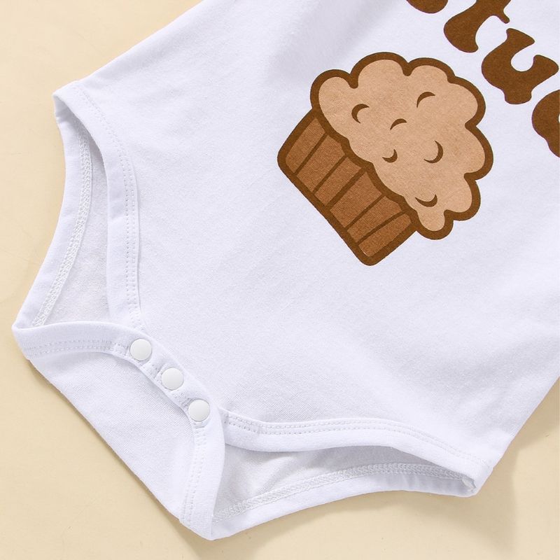 A closeup of the snap clips on a trendy baby boys white bodysuit with a stud muffin print and brown pants clothing set